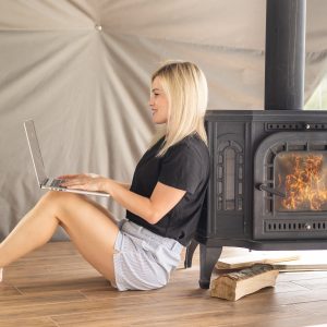 a-woman-works-on-a-laptop-near-a-stove-fireplace-1.jpg